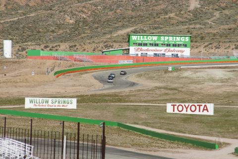 1995 Ford Taurus - Several cars race on a track at Willow Springs, with prominent signage for the venue and Toyota.