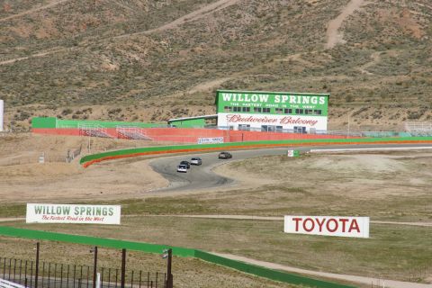 1995 Ford Taurus - Cars navigate a turn on the Willow Springs International Raceway, with the Budweiser Balcony grandstands in the background.