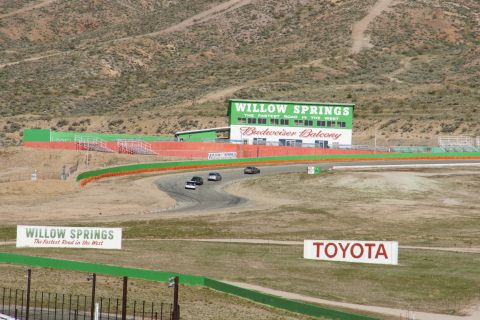 1995 Ford Taurus - Cars navigate a turn at Willow Springs International Raceway under a clear sky.