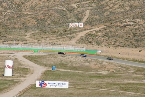 1995 Ford Taurus - A scenic view of a race track multiple vehicles in motion and prominent advertising signage.