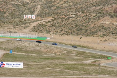 1995 Ford Taurus - Several cars are seen on a race track with a distant sign on the hill.