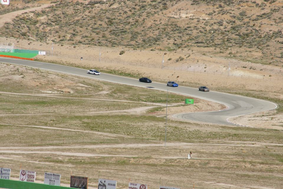 Cars on a race track with dry, hilly terrain