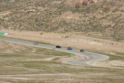 1995 Ford Taurus - Cars navigate a challenging turn on a race track surrounded by arid hills.