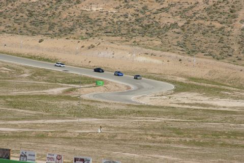 1995 Ford Taurus - Multiple vehicles navigate a challenging race track under a bright sky.