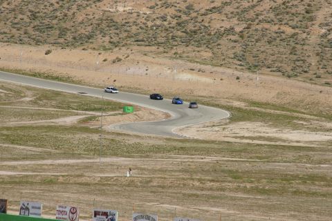1995 Ford Taurus - Cars navigate a turn on a race track under a bright sky.