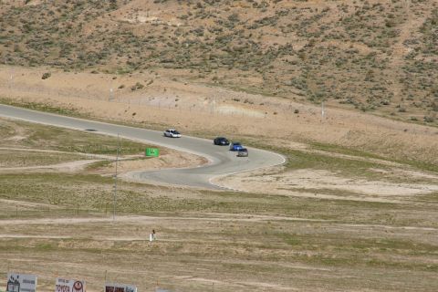 1995 Ford Taurus - Several cars race on a track surrounded by arid hills.