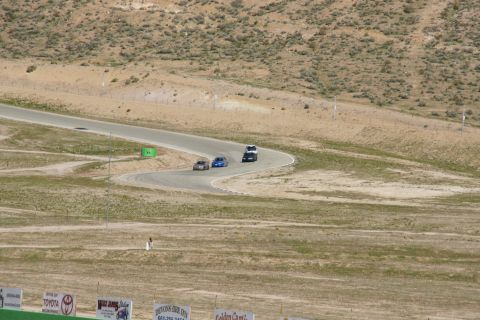 1995 Ford Taurus - Cars navigate a turn on a race track surrounded by arid hills and sparse vegetation.