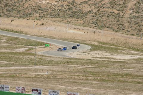 1995 Ford Taurus - Cars navigate a curve on a race track surrounded by arid hills and sparse vegetation.