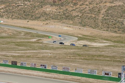 1995 Ford Taurus - Multiple vehicles navigate a challenging race track under a bright sky.