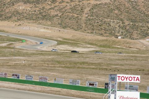 1995 Ford Taurus - Multiple vehicles are seen on a race track with various sponsor signs in the foreground.