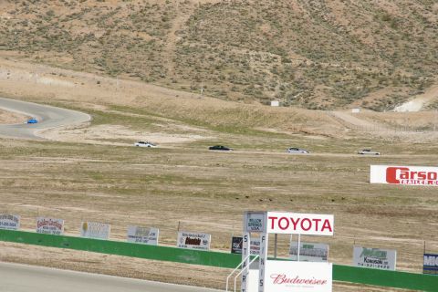 1995 Ford Taurus - Several cars are on a winding race track with dry grass and hills in the background. Signs for various sponsors are visible.