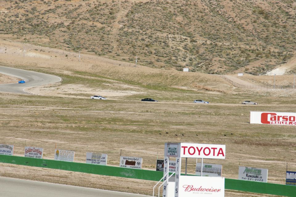 Cars on a race track with hills and signs for Toyota and Budweiser