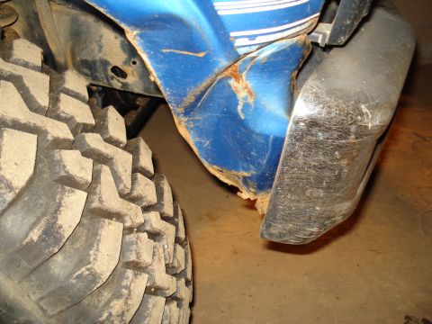 1985 Ford F-150 - Close-up view of a damaged blue fender and a tire on a vehicle.