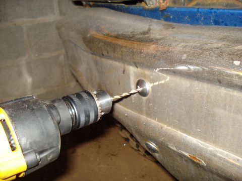 1985 Ford F-150 - Drilling a hole in a vehicle's bumper to install a fastener.