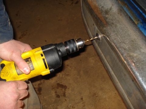1985 Ford F-150 - A yellow drill is used to make a hole in a vehicle's chrome bumper.