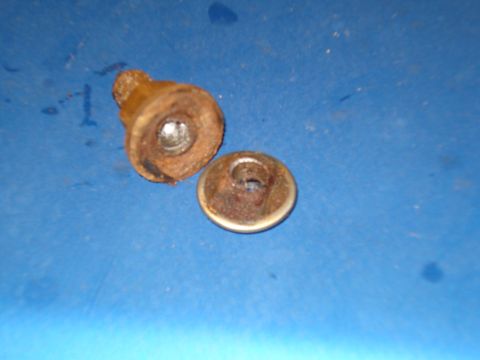 1985 Ford F-150 - Two old, rusted metal fasteners sit on a blue surface.