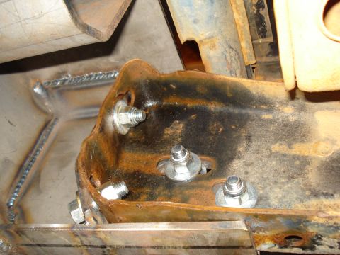 1985 Ford F-150 - Close-up view of a rusted metal bracket with bolts and fresh welds, indicating repair or modification.