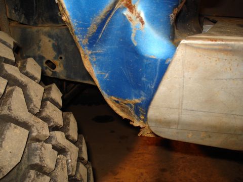 1985 Ford F-150 - Close-up view of a blue fender flare and a large off-road tire, showing rust and wear.