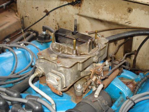 1967 Ford F-250 - A detailed view of a vehicle's engine carburetor, showing its mechanical components and surrounding wiring.