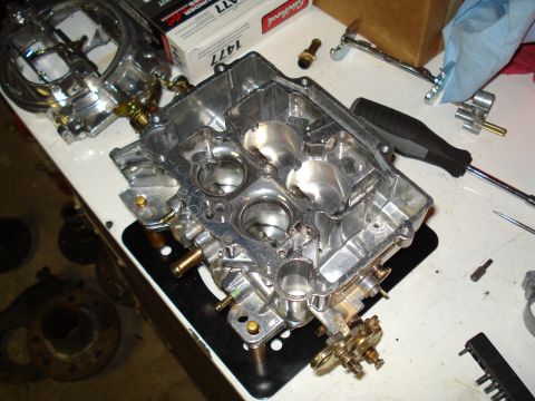 1967 Ford F-250 - A disassembled carburetor sits on a workbench next to a screwdriver and a box of parts.