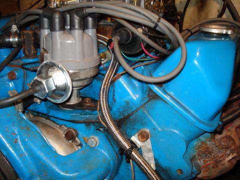 1967 Ford F-250 - Close-up view of an engine's distributor and a bright blue valve cover with various hoses and wires attached.