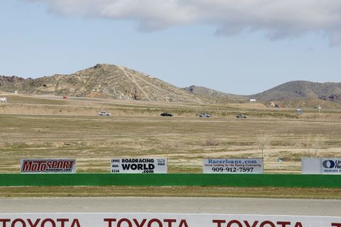1995 Ford Taurus - Cars race on a track with mountains and advertising banners in the background.