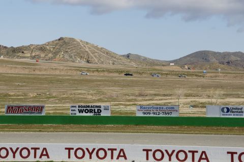 1995 Ford Taurus - A race track scene with multiple vehicles visible in the distance and various sponsor advertisements along the trackside.