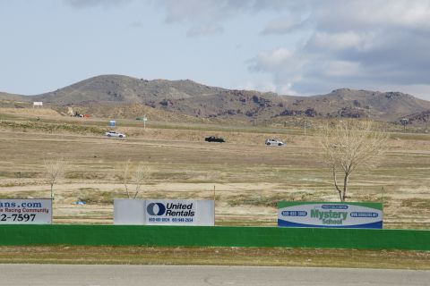 1995 Ford Taurus - Cars are seen driving on a track with a dry, hilly landscape and cloudy sky.