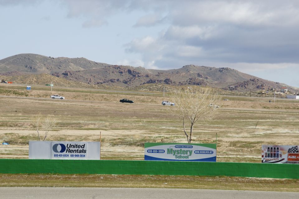 Two cars on a dry racetrack with mountains in the background