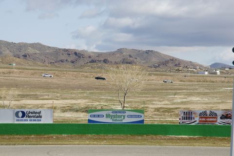 1995 Ford Taurus - Cars on a race track with mountains and advertising signs in the background.