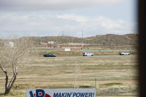 1995 Ford Taurus - Cars race on a track under a cloudy sky, with a sign that says 'MAKIN' POWER!' in the foreground.