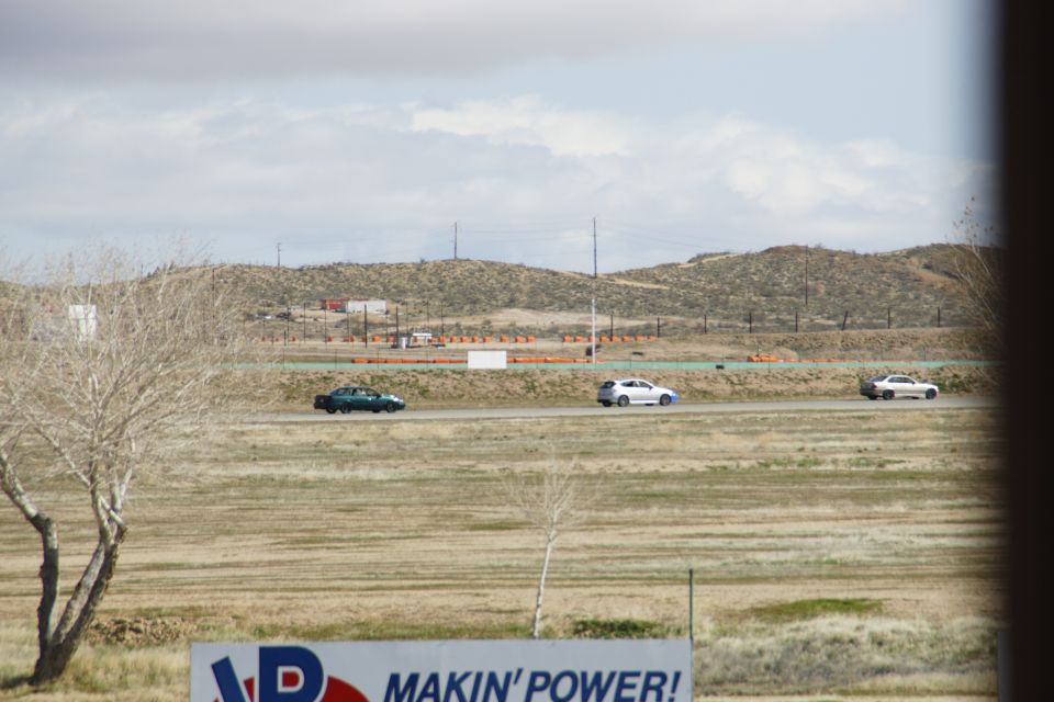 three cars driving on a track with hills in the background