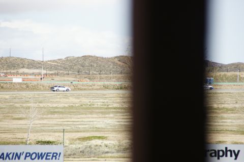 1995 Ford Taurus - A view of a racetrack with two cars driving, framed by a dark vertical element.