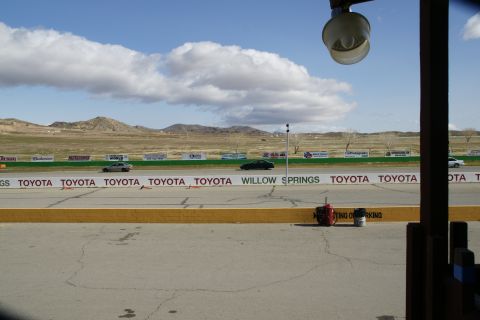 1995 Ford Taurus - Cars on a race track with mountains and clouds under a bright sky.