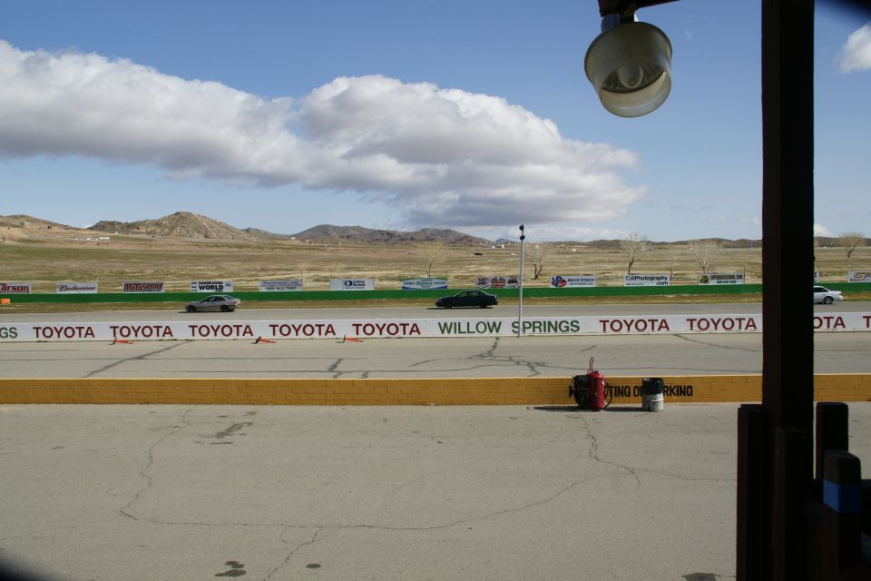 Race track with Toyota sponsorship banners and cars driving, mountains in background