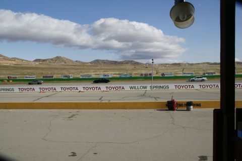 1995 Ford Taurus - A view of a race track with several cars driving under a cloudy sky.