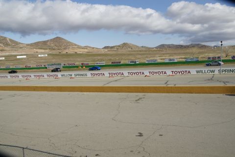 1995 Ford Taurus - Several cars are racing on a track with mountains in the background and Toyota banners along the side.