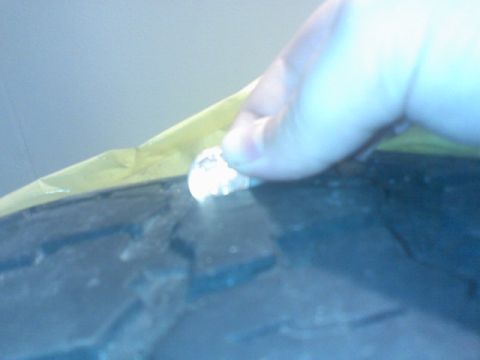 1996 Ford Bronco - A finger touches a small object on a tire, partially covered by yellow tape.