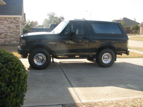 1996 Ford Bronco - Side profile of a black 1996 Ford Bronco parked on a driveway.