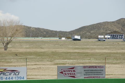 1995 Ford Taurus - A wide shot of a race track facility with vehicles and buildings under a hazy sky.