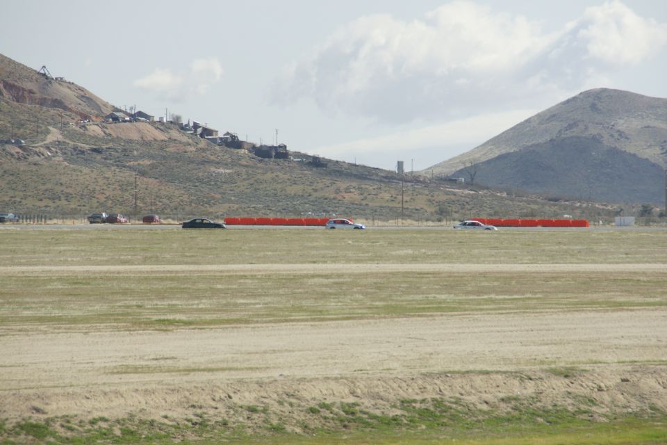 Cars on a track with orange barriers and a hillside town