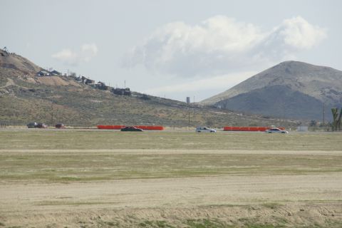 1995 Ford Taurus - Cars on a track with hills and buildings in the background.
