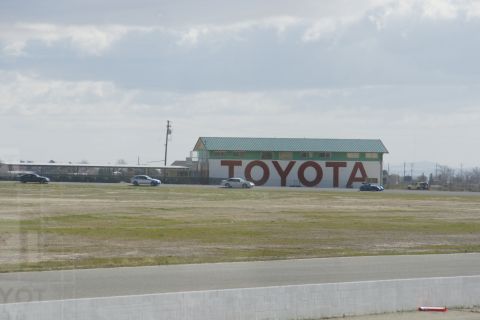 1995 Ford Taurus - Cars are seen driving on a track with a large TOYOTA sign in the background.