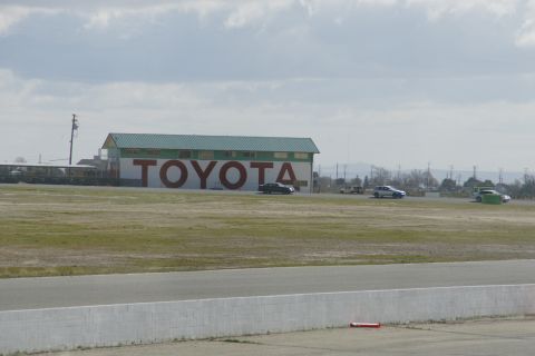 1995 Ford Taurus - Several cars are visible on a racetrack in front of a building with a large TOYOTA logo.