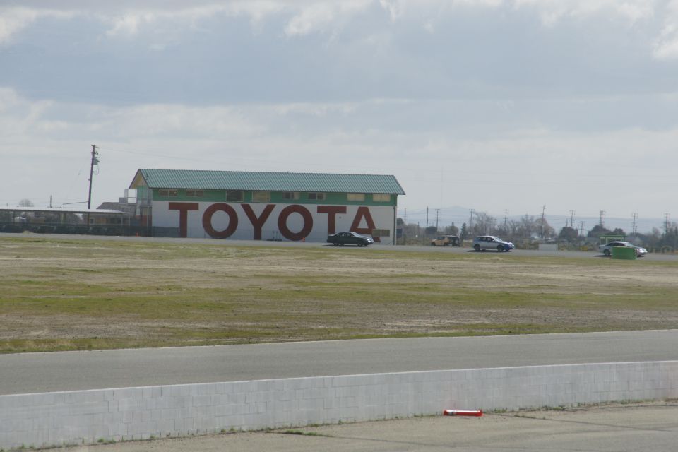 Cars on a racetrack with a large TOYOTA building