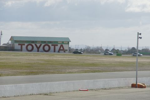 1995 Ford Taurus - Cars drive on a track in front of a building with a large TOYOTA sign.