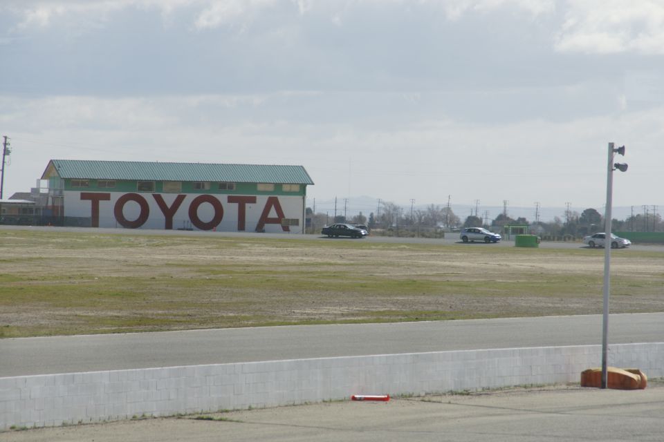 Toyota building with large sign, cars driving on a track in front of it