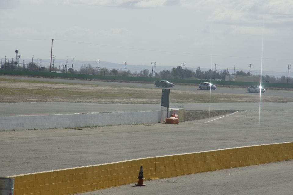 three cars driving on a racetrack with power lines and trees in the background