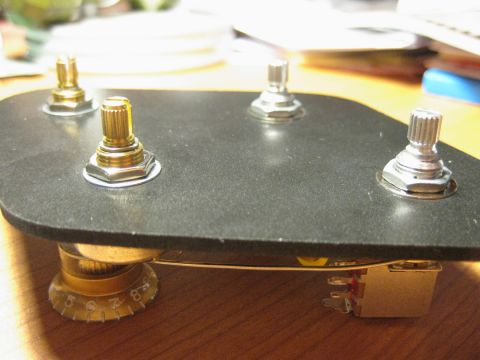 1989 Mazda MX-6 - Close-up view of a guitar's control plate four knobs and a switch, with a numbered dial visible on one of the potentiometers.