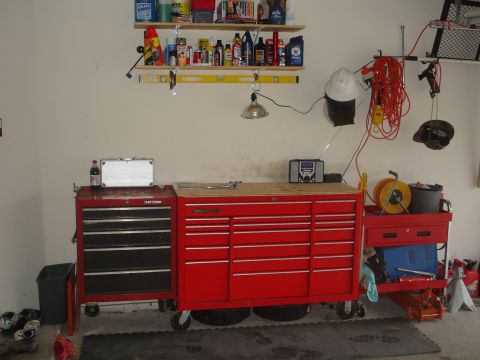 1989 Ford Bronco - Garage scene with a large red tool chest, workbench, and shelves stocked with supplies.